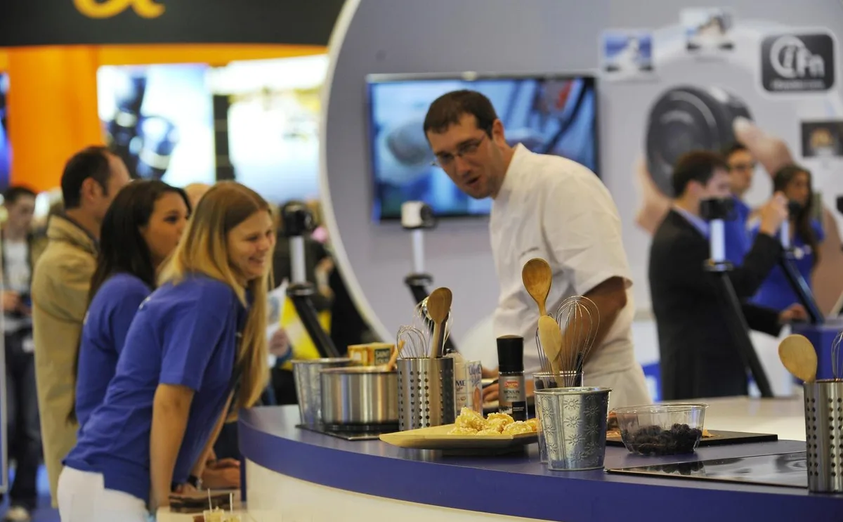 Un chef Animation Chef en démonstration culinaire devant des visiteurs, sur un stand d'exposition