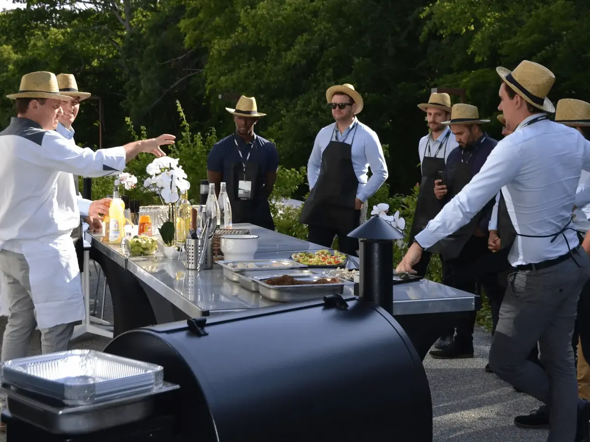 Chefs et invités réunis autour du barbecue lors d'une Grill Party en extérieur