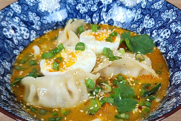 Bol de soupe gyoza au bouillon coco-cacahuète et nouilles udon