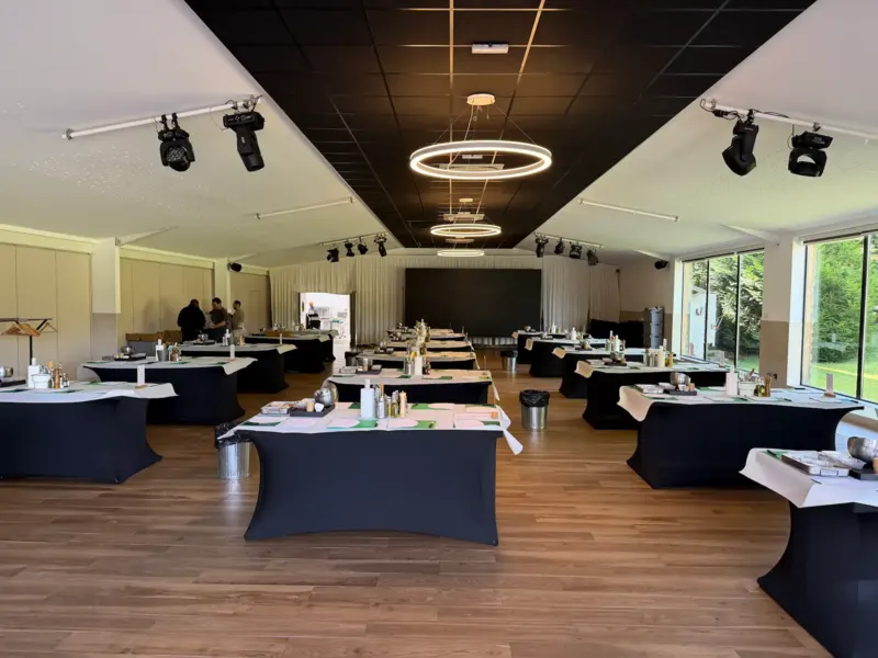 Grande salle aux tables noires dressées, baies vitrées sur le jardin