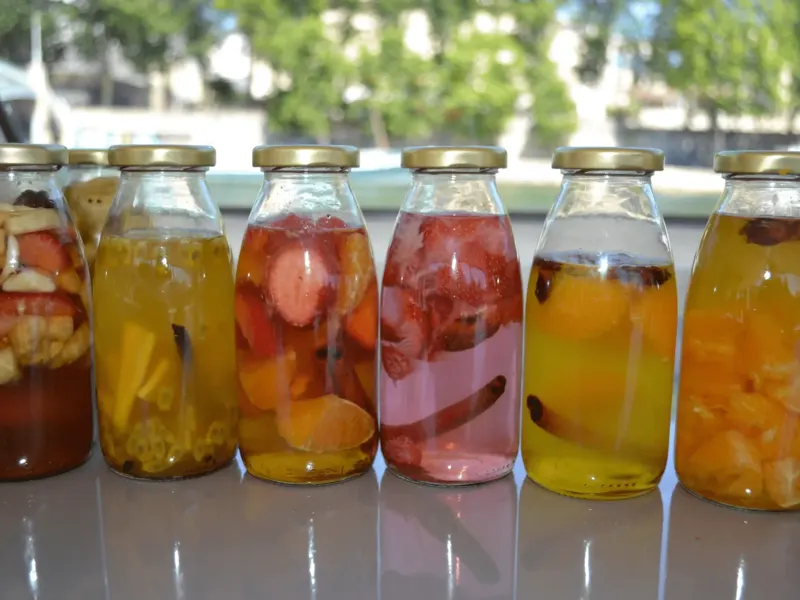 Bouteilles de rhums arrangés aux fruits alignées en terrasse
