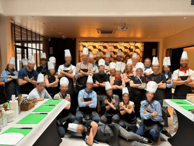Chef versant une sauce sur une assiette, participant regardant le dressage