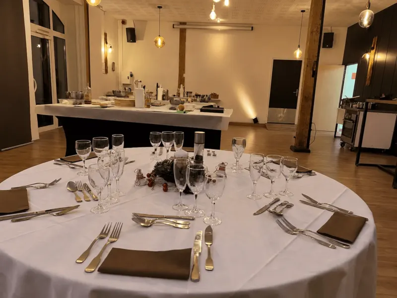 Table ronde dressée au premier plan, plan de travail de l'atelier en arrière-plan