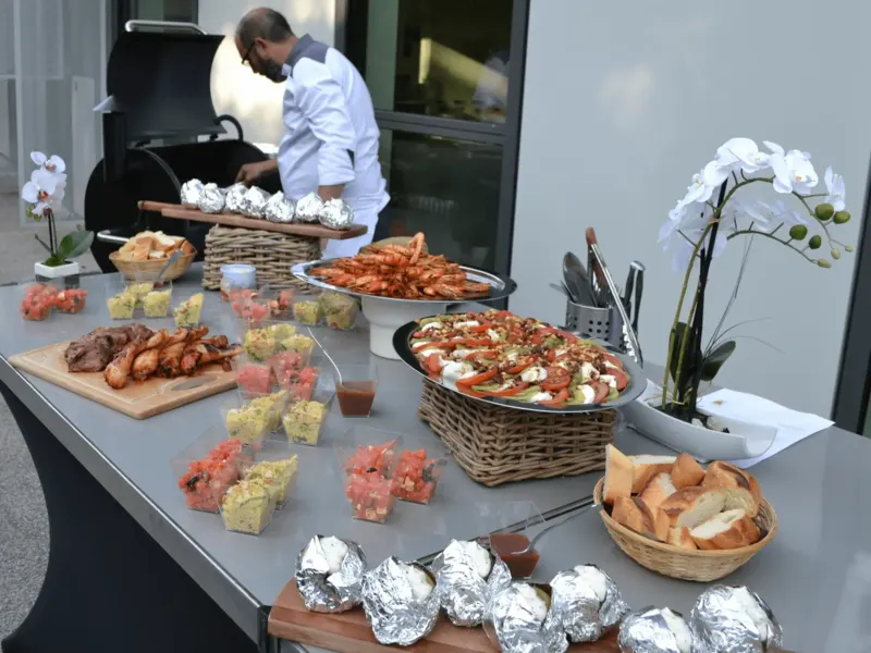 Chef au barbecue près d'un buffet de gambas et brochettes