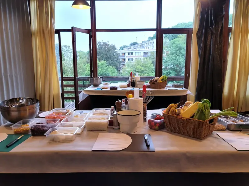 Table d'atelier dressée devant une baie vitrée avec vue sur les arbres