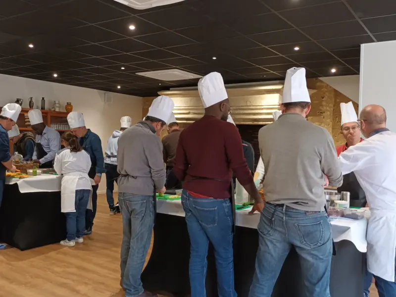 Participants en toque préparant leurs poké bowls autour des tables