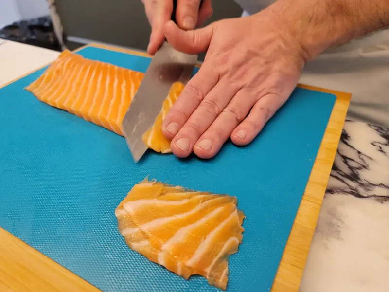 Chef tranchant finement un filet de saumon frais