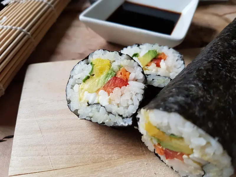 Makis californias coupés sur planche, sauce soja en coupelle