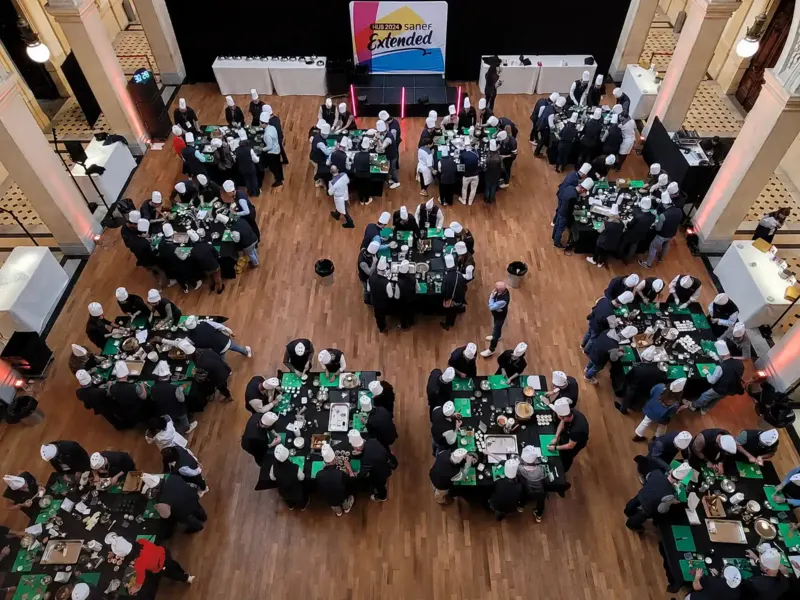 Grand groupe de participants autour de tables rondes