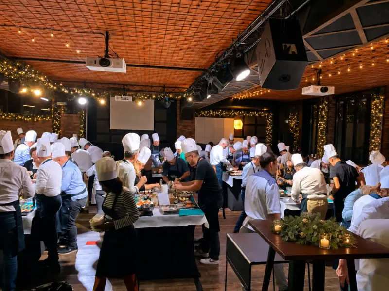 Nombreux participants en toques cuisinant dans une salle guirlandée