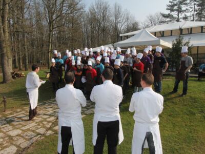 Brief des chefs devant un grand groupe de participants en toque, en extérieur
